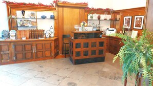 Interior de madeira com chão de azulejos, uma planta e vários objetos nas prateleiras.