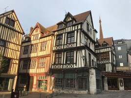 Um edifício tradicional em estilo de enxaimel com uma torre imponente, entrada no nível da rua e uma placa visível.