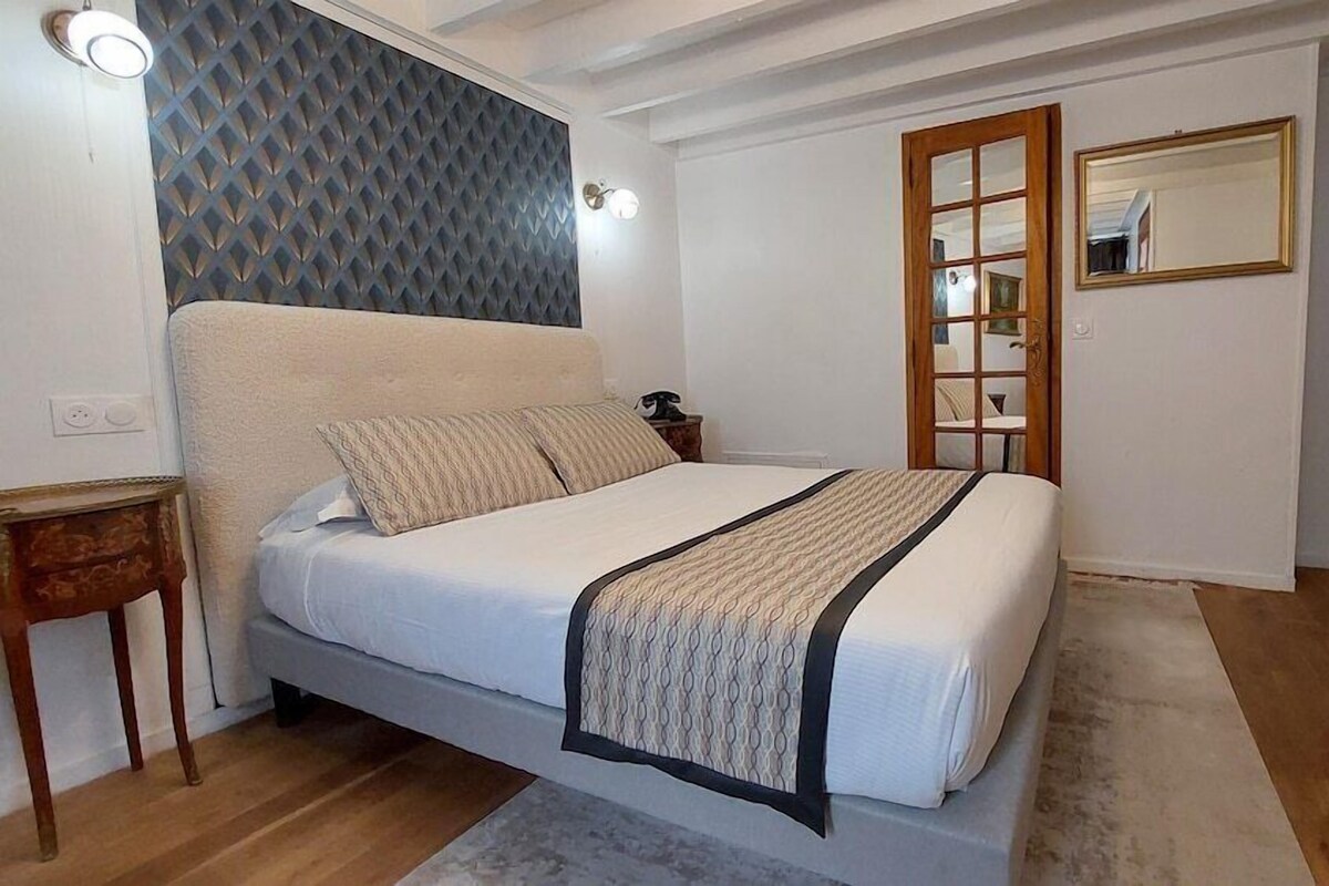 A bedroom with a bed, bedside table, and a mirror.