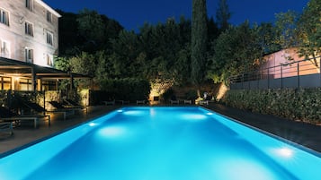 Una piscina al aire libre de temporada, sombrillas