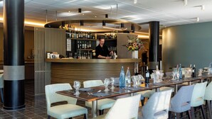 A modern restaurant with a bar area, neatly arranged tables, and a bartender.