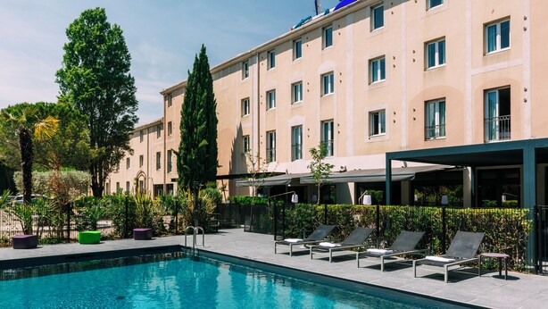 A swimming pool with lounge chairs and a building with multiple windows. - Escale Oceania Aix-en-Provence (Aix-en-Provence)