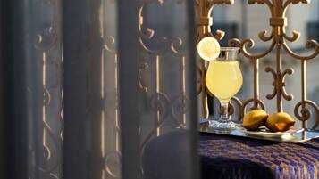 A balcony with a table set for two, featuring a glass of drink and two pastries.