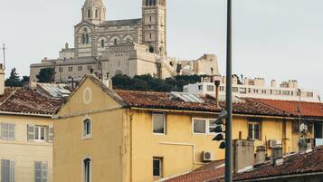 Un bâtiment historique doté d’une tour et d’un dôme imposants, entouré d’immeubles d’habitation aux toits recouverts de tuiles rouges et à l’architecture traditionnelle.