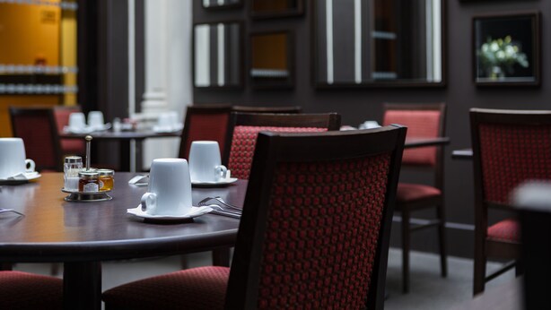 A dining area with tables set for two, each with white cups and saucers, and a small condiment station. - Escale Oceania Marseille Vieux Port (Marseille)