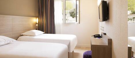 A hotel room with two beds, a small desk with a telephone, and a TV mounted on the wall.