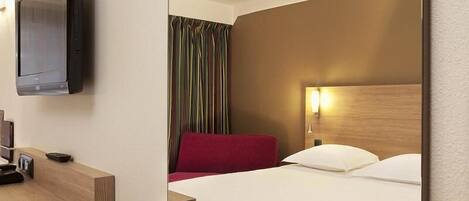 Habitación de hotel con cama, escritorio y televisor de pantalla plana, además de una silla roja.