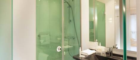 A modern bathroom with a glass-enclosed shower, a black sink, and a mirror.