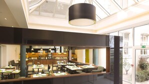 Un comedor moderno con una barra alargada, varias mesas y una zona de cocina central.