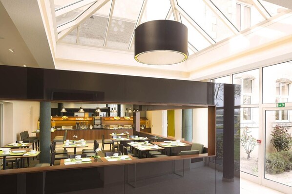 Un comedor moderno con una barra alargada, varias mesas y una zona de cocina central.