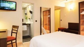 A hotel room with a bed, a TV, a desk, a chair, a mirror, and a wardrobe. - Escale Oceania Vannes (Vannes)