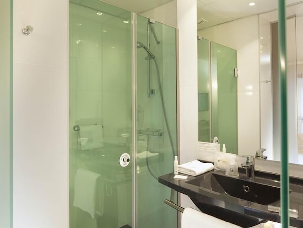 A modern bathroom with a glass-enclosed shower, a black sink, and a mirror.