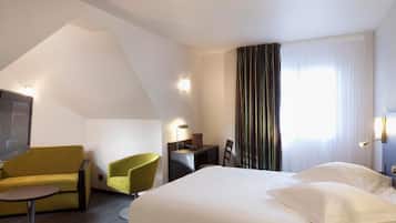 A hotel room with a bed, a desk, a chair, a television, and a window with curtains.