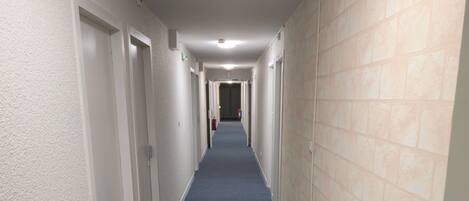 A long, narrow hallway with carpeted floors and white walls.