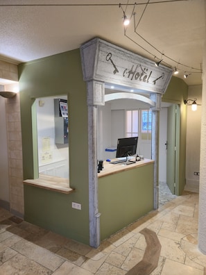 A reception desk with a sign that reads "Hotel" and a computer monitor.