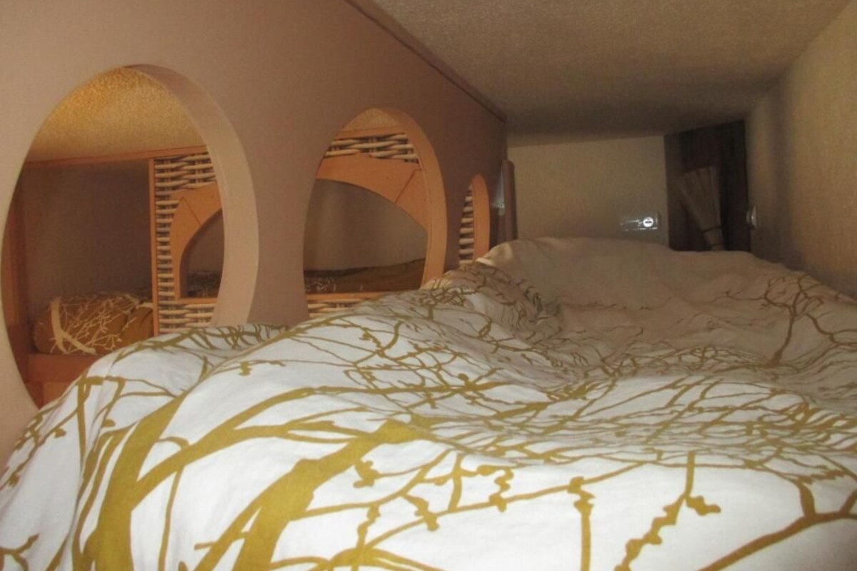 A room with a bed, arched alcoves, and a view of the city.