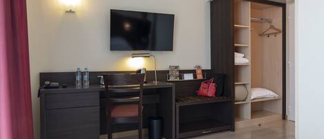 Habitación de hotel con escritorio, silla, televisión y vestidor.