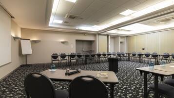 A conference room with a long table, chairs, a whiteboard, and a projector.