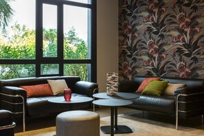 Relax in this stylish living room with a sofa, coffee table, and ottoman, surrounded by lush views and decorative touches.