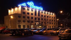 Un hotel con un letrero de neón, varios pisos y un estacionamiento lleno de coches.