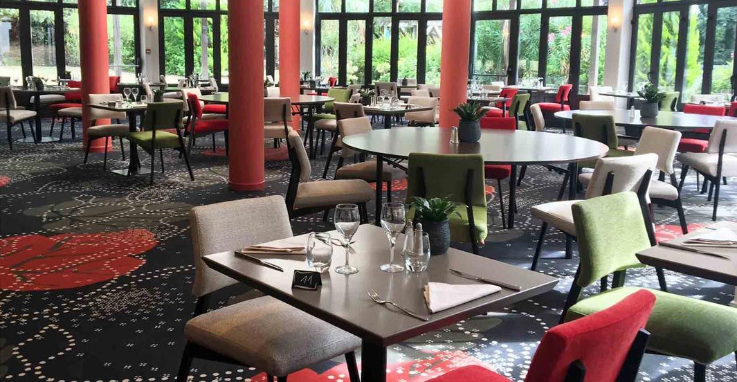 Un restaurante con mesas y sillas redondas, algunas con cojines rojos.