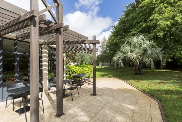 An outdoor patio with a pergola, tables, and chairs.