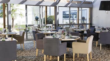 Un restaurante con una decoración moderna, amplios ventanales y un suelo con diseño de piedra.