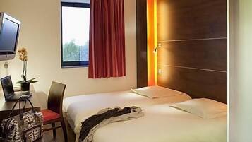 Habitación de hotel con dos camas, un escritorio con una computadora portátil, un televisor y una ventana con cortinas.
