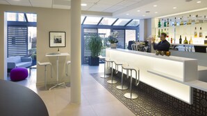 A modern bar area with a counter, stools, and a variety of bottles.
