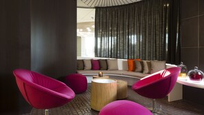 A modern lounge area with a curved sofa, vibrant red chairs, and a wooden coffee table.