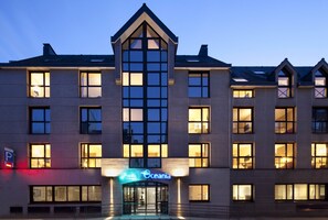 A multi-story hotel with a prominent entrance and illuminated signage. - Escale Oceania Quimper (Quimper)
