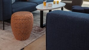 A modern living room with a blue sofa, a round coffee table, and a view of the beach. - Hotel Oceania Saint Malo (Saint-Malo)