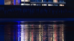 A modern building with multiple floors and large windows, reflecting lights on the water in front. - Hotel Oceania Saint Malo (Saint-Malo)