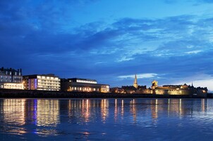 A waterfront cityscape with historic buildings and a prominent tower.