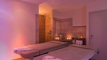 Relax in a serene spa room with two massage tables, a large mirror, and soothing ambiance.