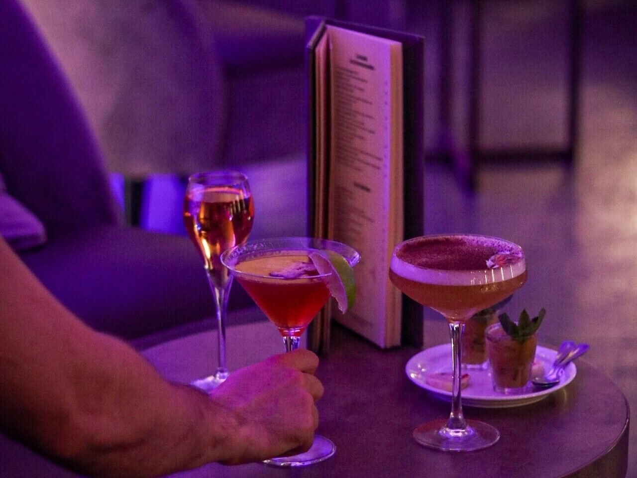 A table with two cocktails and a menu.