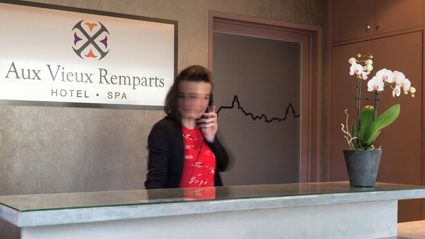 A hotel reception desk with a logo and name 'Aux Vieux Remparts HOTEL • SPA' above it. - Hôtel Aux Vieux Remparts (Provins)