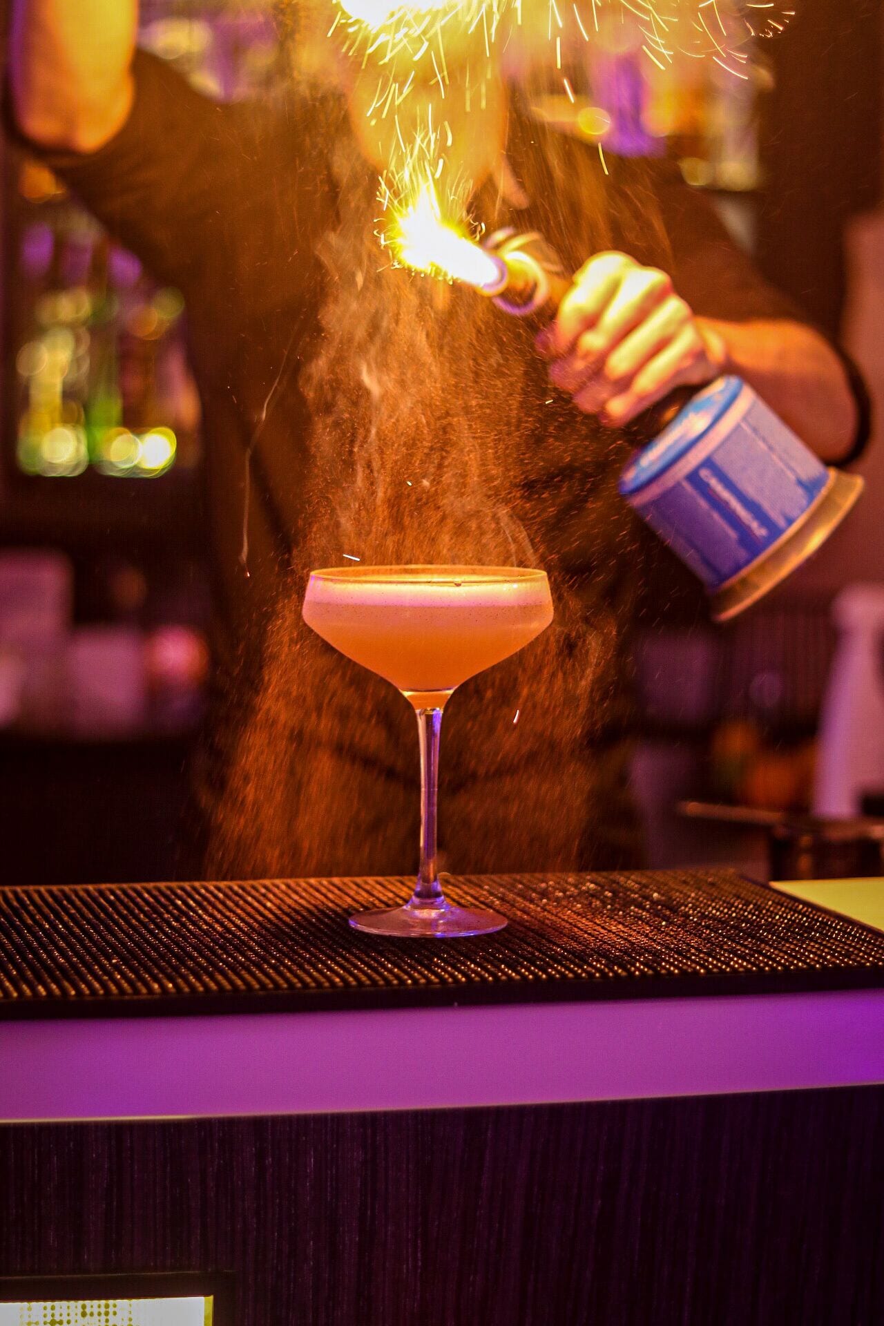 Un camarero sirviendo una bebida en una copa de martini con una chispa.