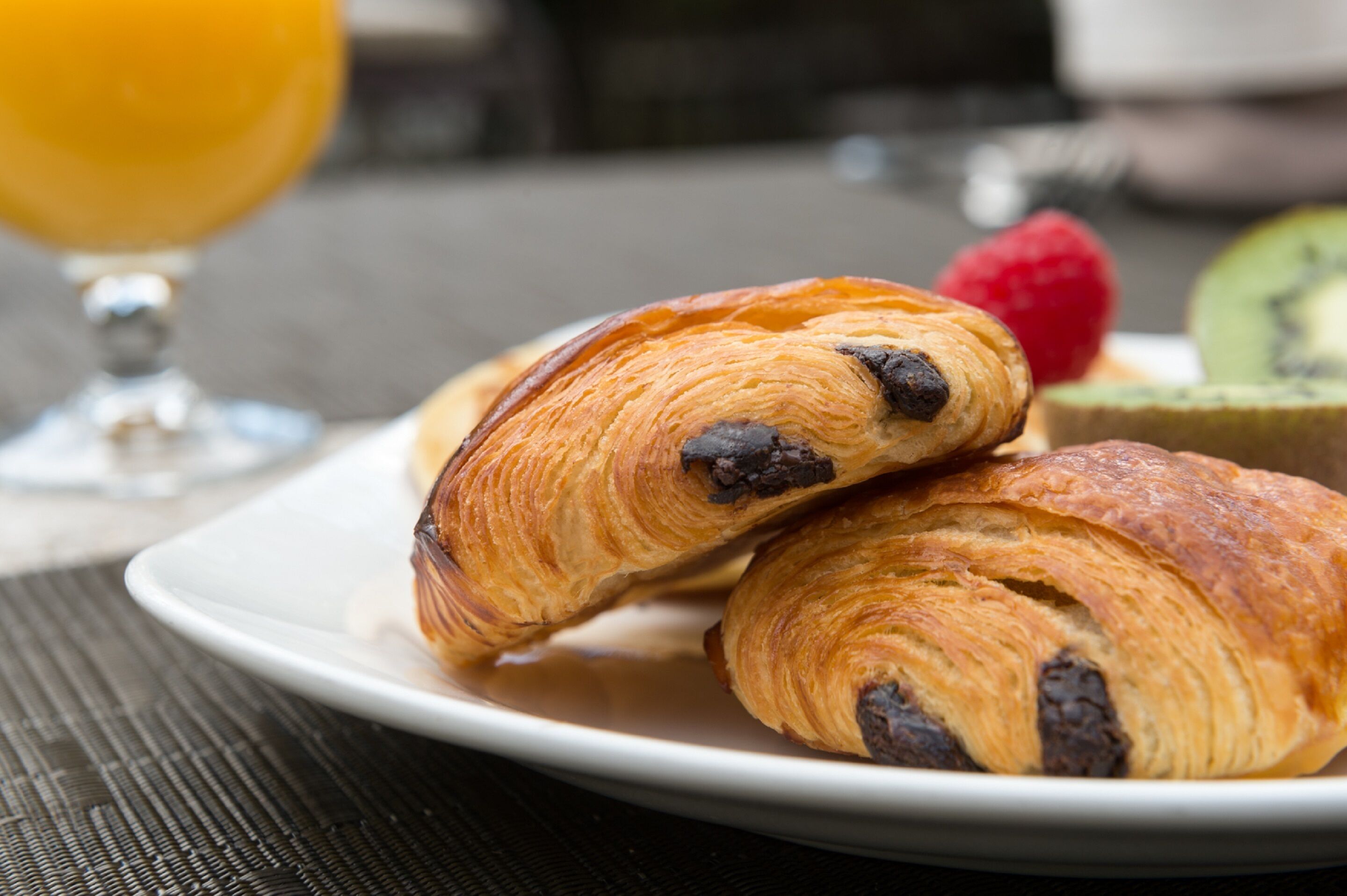 A plate with croissants and a glass of orange juice.