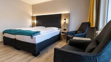 Una habitación de hotel con cama, escritorio, silla y mesita de noche.