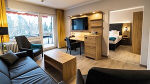 A modern hotel room with a sofa, a desk, a television, and a bed. - VitalHotel Ascona (Bad Bevensen)