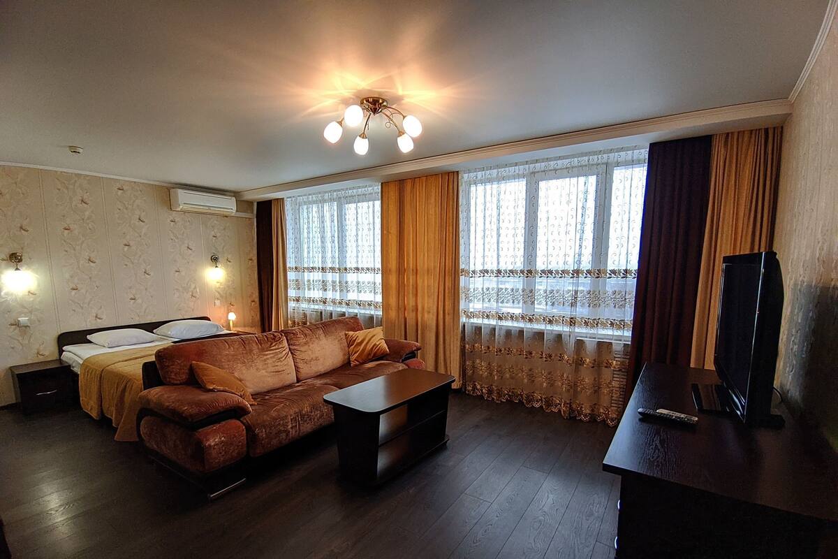 Una habitación con cama, sofá, televisión y escritorio.