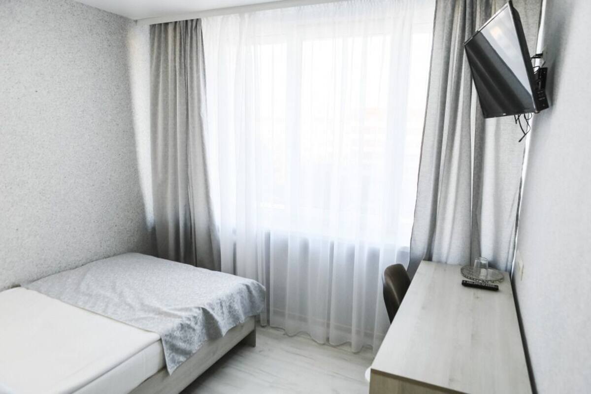 Una habitación pequeña y ordenada con una cama individual, un escritorio y una silla.