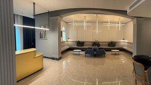 Un área de recepción moderna con una pared curva, un mostrador amarillo y arreglos de asientos.