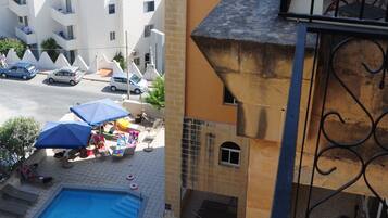 Ein Gebäude mit Pool, Meerblick und einem Balkon mit Tisch und Stühlen.