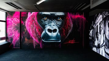 Une pièce ornée d’une grande fresque représentant un gorille, d’une photographie en noir et blanc accrochée au mur et dotée d’une fenêtre bien visible.