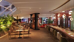 Amplio espacio interior con diversas opciones de asientos, una zona de bar y vistas de la ciudad a través de grandes ventanales.