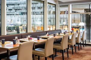 Un restaurante con una barra larga, cabinas y vistas a un edificio moderno.