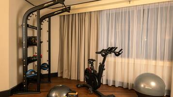 Un gimnasio en casa con barra de dominadas, bicicleta estática, balón medicinal y banco de pesas.