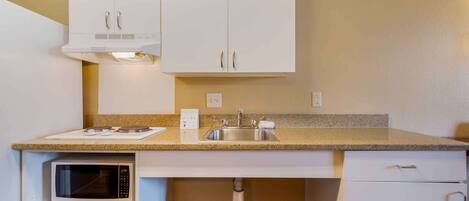 Una kitchenette compacta con microondas, pileta y placares.